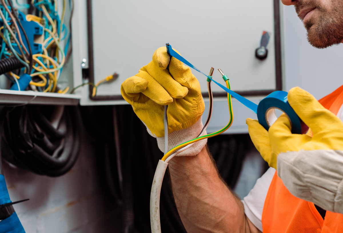 Close-up of a worker's gloved hand on a metal structure.