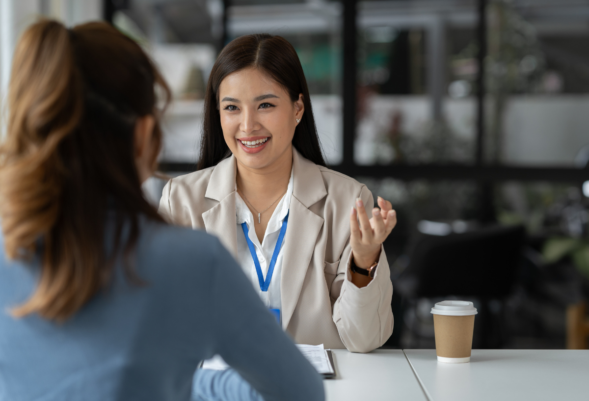 Woman in an office, smiling and looking at another woman