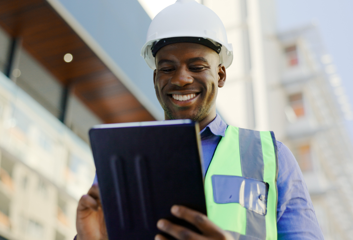 man in a white hard hat writing on a tablet.