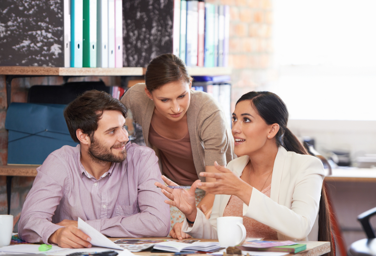 Man and 2 women in an office meeting.