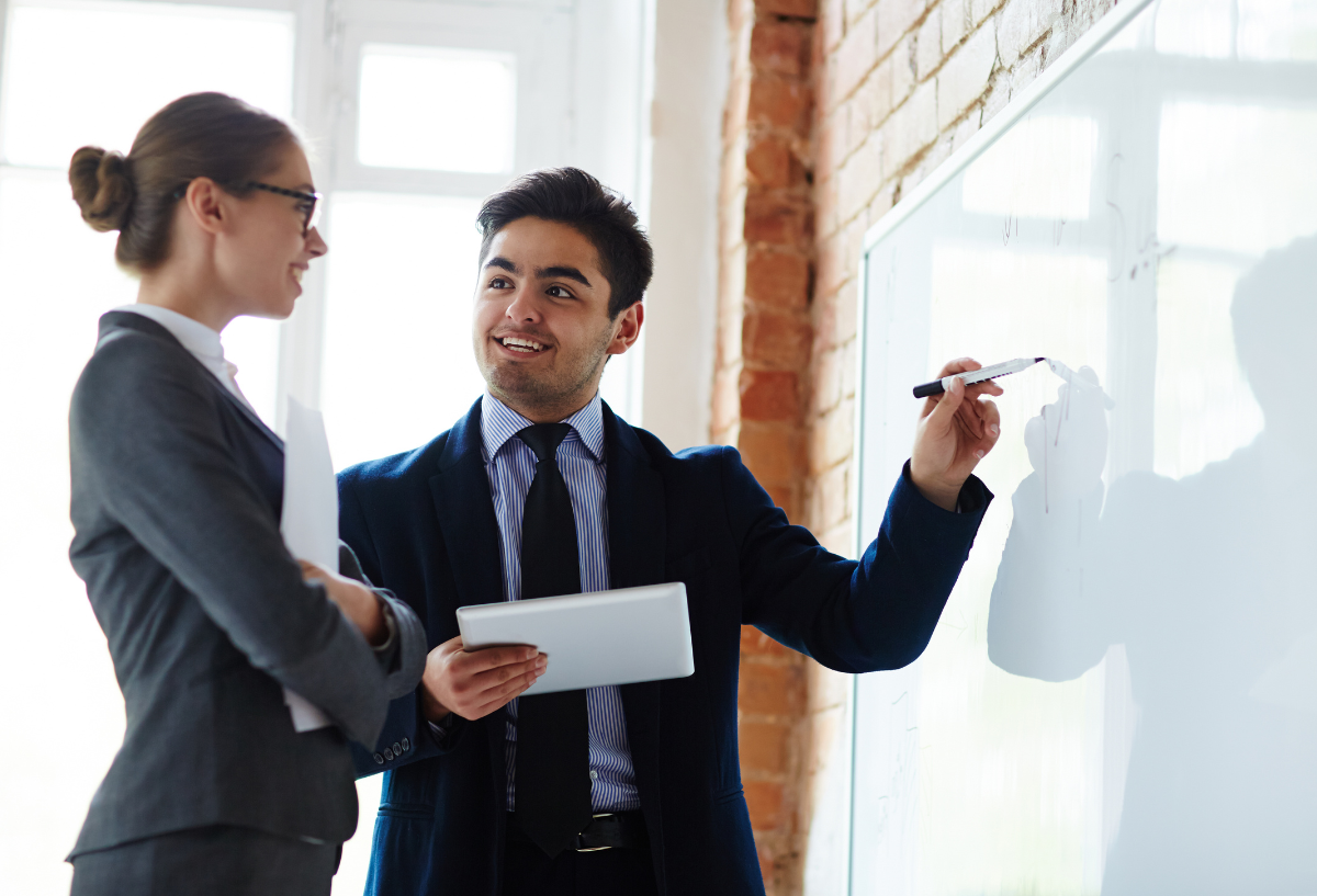 Man in a suit presenting to a woman in an office.