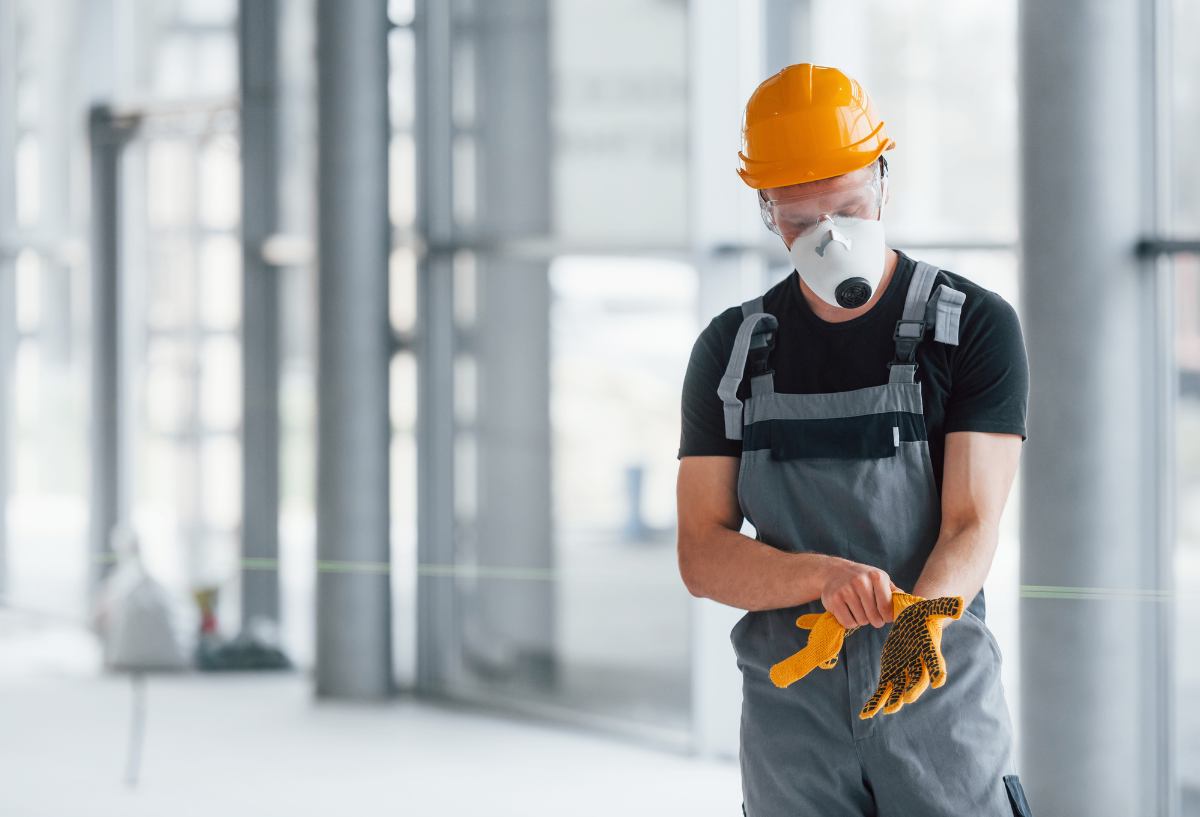 person putting on yellow gloves while wearing hard hat