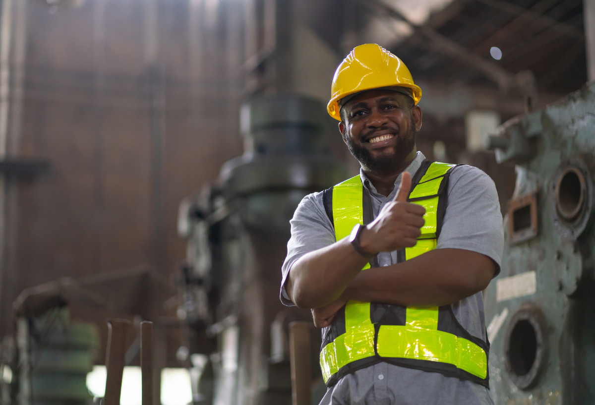 Worker in a high-visibility yellow vest and hard hat in a factory.