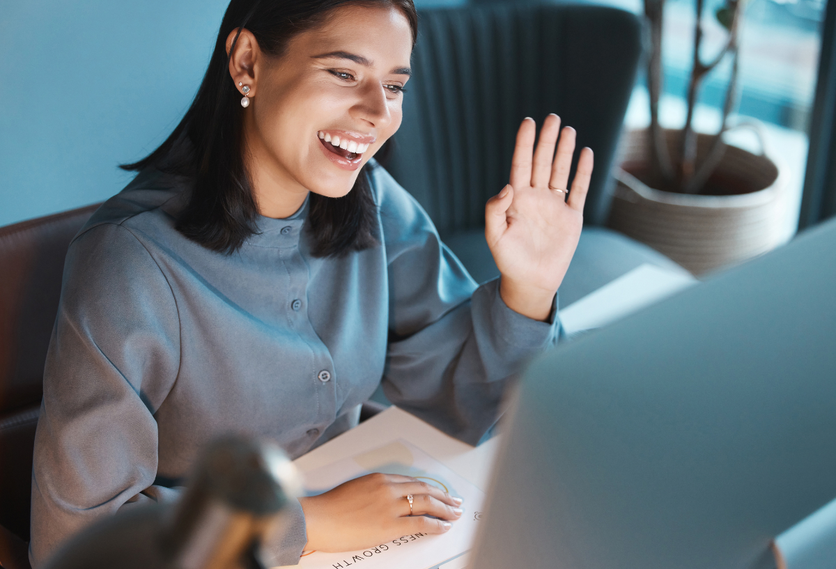 Woman in an office, smiling and looking at a monitor.