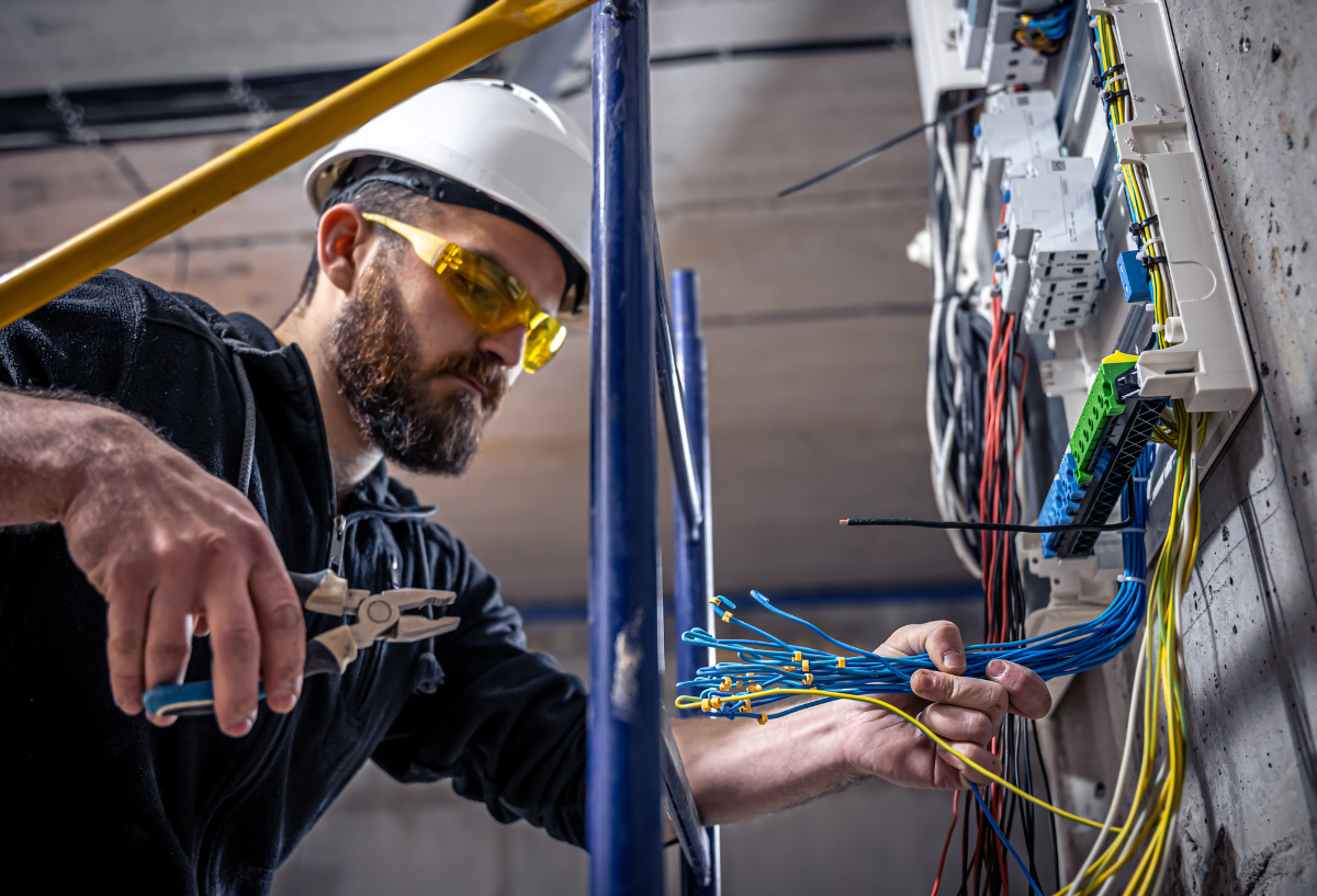 Worker in a hard hat and safety glasses operating machinery.