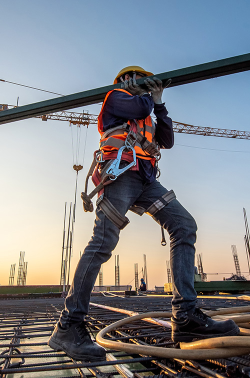 Worker in a yellow hard hat and full-body safety harness.