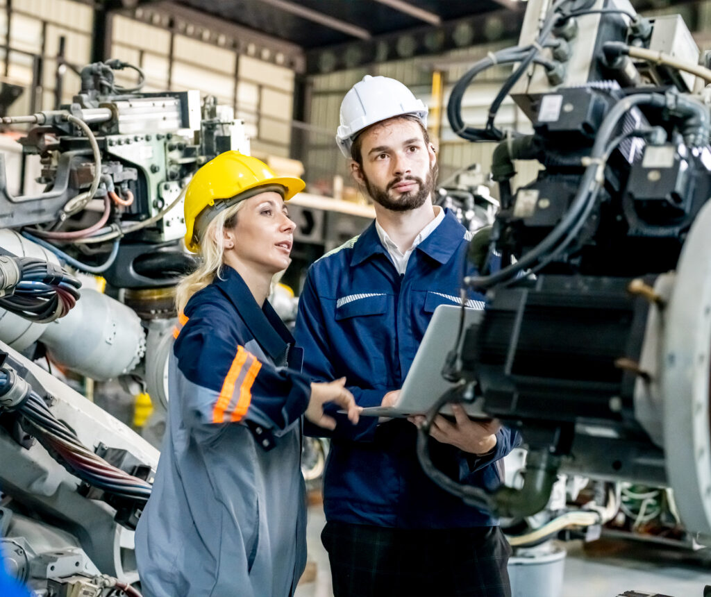 Two workers in safety gear operating industrial machinery.