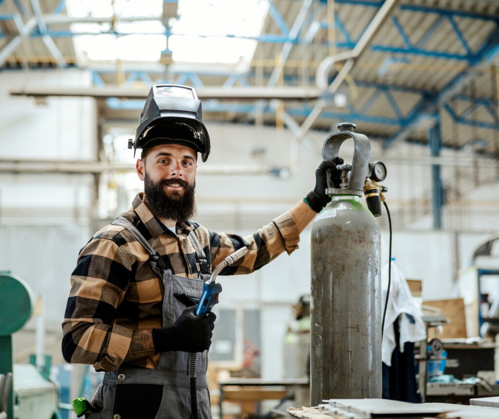 Man with a beard in a warehouse, using a tool.