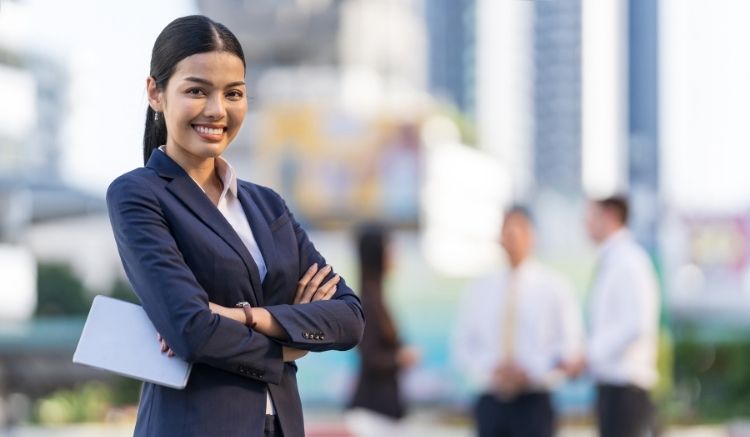 Woman in a business suit with arms crossed, smiling.