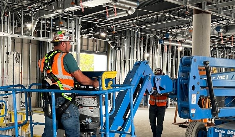 Construction worker in an orange vest on a blue machine