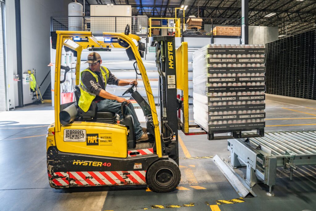 Worker operating a small yellow forklift indoors.