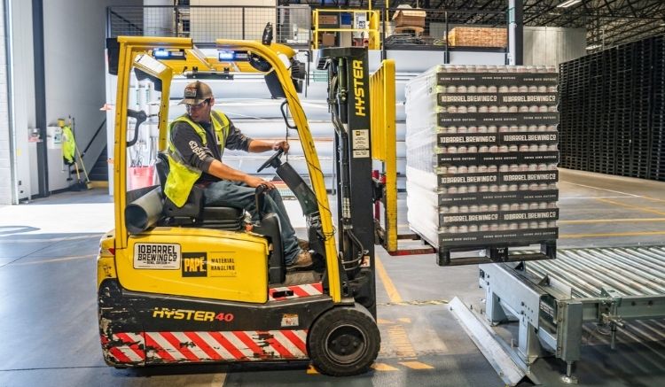 Worker operating a small yellow forklift