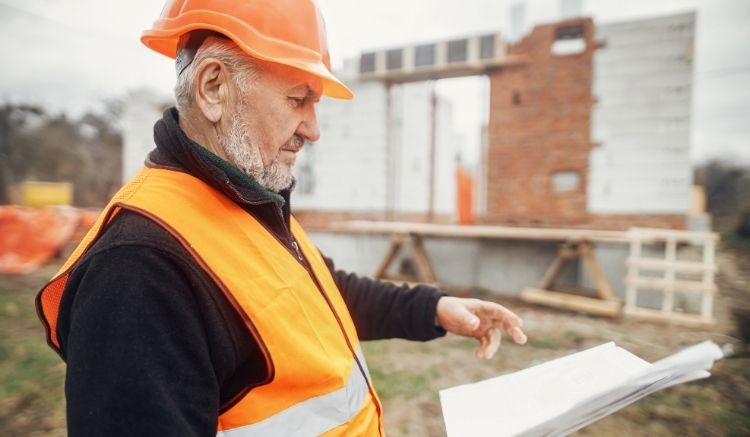 Construction worker in an orange vest reviewing a document.