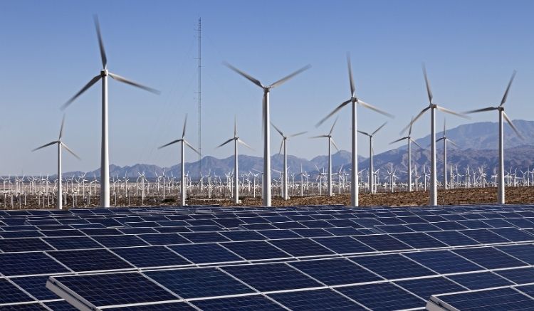 A field of wind turbines and solar panels on a sunny day.