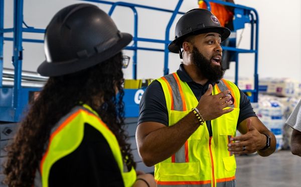 workers, including one woman, in hard hats and vests.