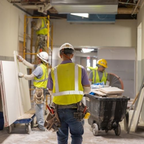 men in hard hats and yellow safety vests working inside a building