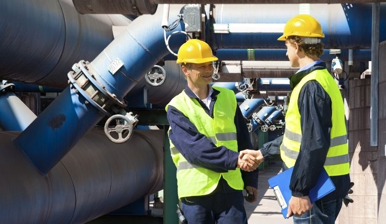 Two workers in hard hats and vests shaking hands