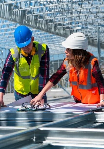 Two workers in hard hats reviewing blueprints.
